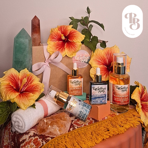 Paradise Bay skincare products with flowers and crystals on a textured surface